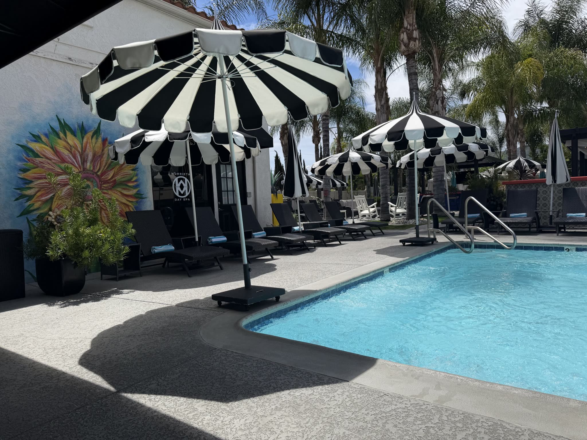 The heated outdoor pool, striped cabana umbrellas and sunflower mural at Murrieta Day Spa